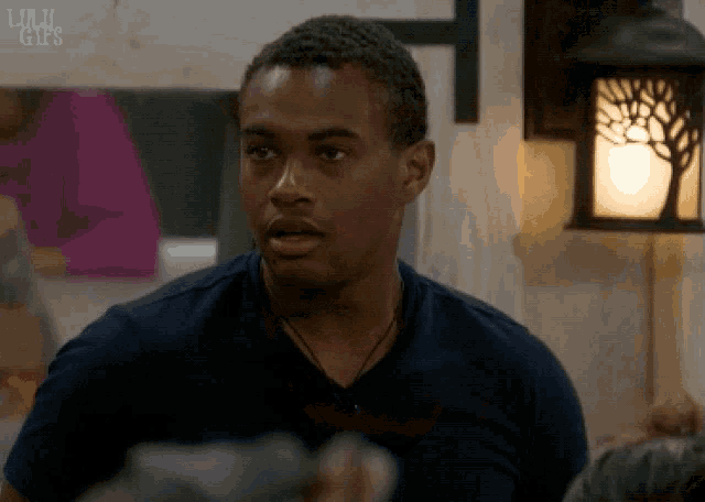 a man in a blue shirt is standing in front of a lamp with the words lulu gifs on the bottom
