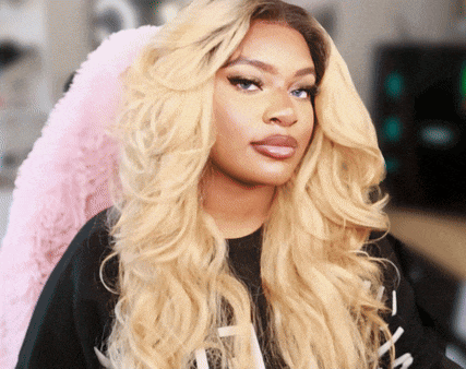 a woman with long blonde hair is wearing a black shirt that says ' i ' on it