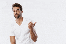 a man in a white t-shirt is giving a thumbs up sign
