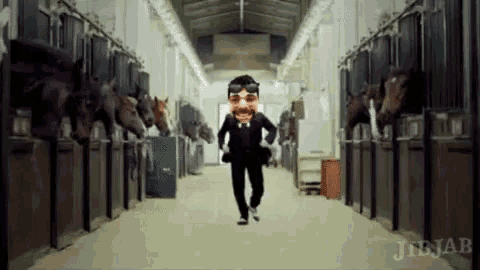 a man in a suit and goggles is running through a stable with horses