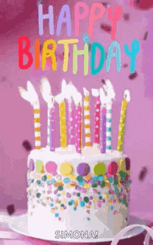a birthday cake with candles and sprinkles is on a table .