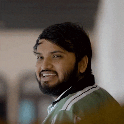 a man with a beard and a green jacket smiles