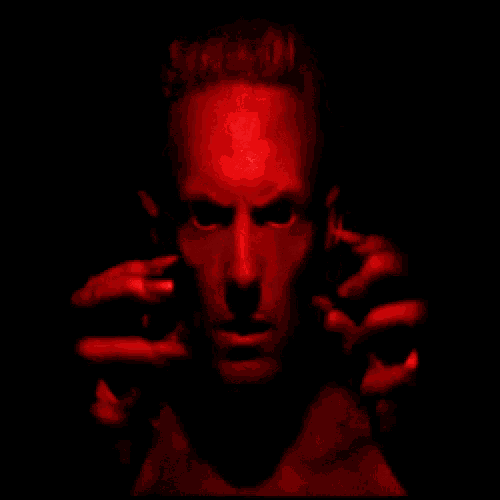 a man 's face is lit up in red and his hands are behind his ears