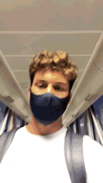 a man wearing a face mask is standing in a train