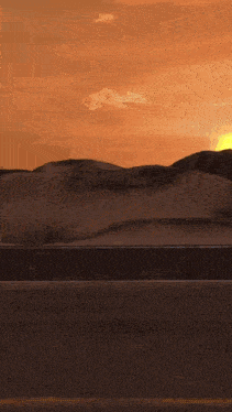 a sunset over a desert landscape with a few mountains in the background
