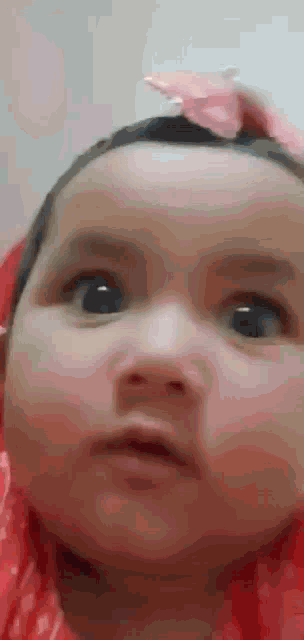 a baby with a pink bow on her head is making a funny face .