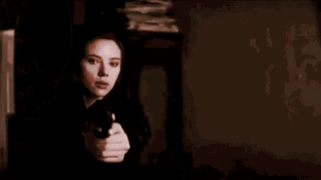 a woman is pointing a gun at the camera .