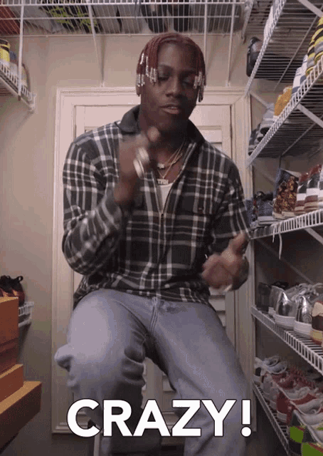 a man in a plaid shirt is sitting in a closet and the word crazy is on the bottom right