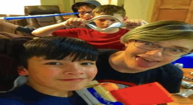 a group of young boys are taking a selfie with a spoon .