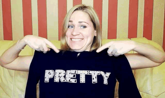 a woman is pointing at a shirt that says pretty on it