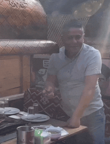 a man in a white shirt is dancing in front of a sign that says ' markamangalbasii '