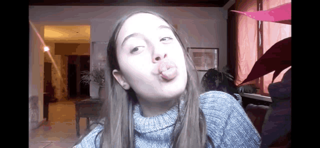 a girl wearing a turtleneck sweater is making a funny face