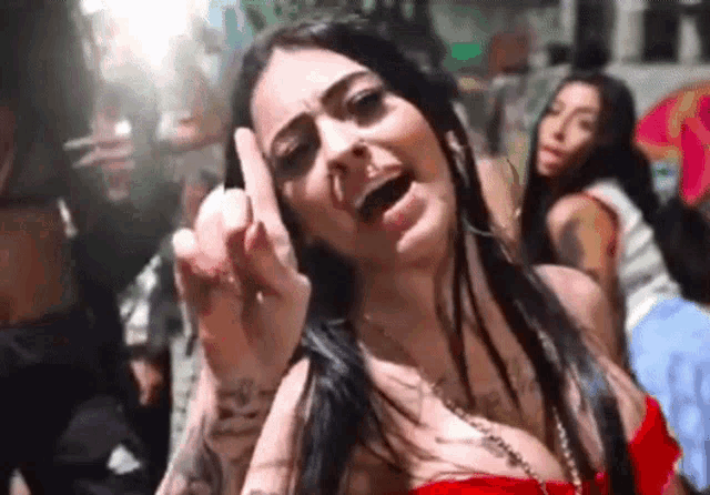 a woman in a red dress is giving the middle finger to the camera .