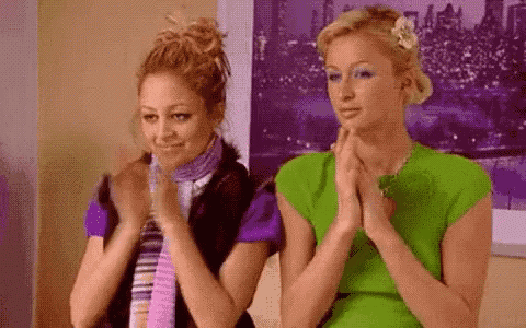 two women are sitting next to each other on a couch and clapping .