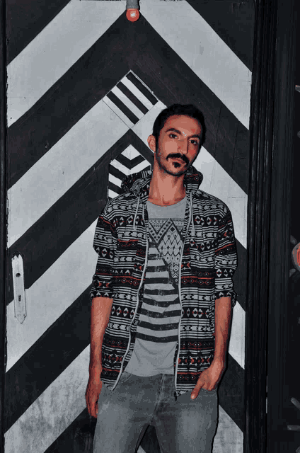 a man stands in front of a black and white striped door