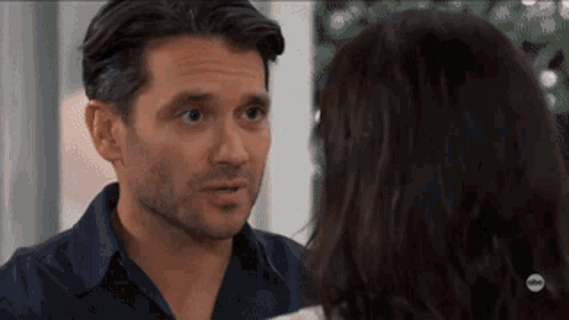 a man and a woman are looking at each other and the man is wearing a blue shirt .