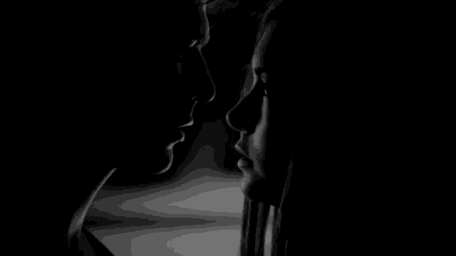 a black and white photo of a man and woman looking at each other