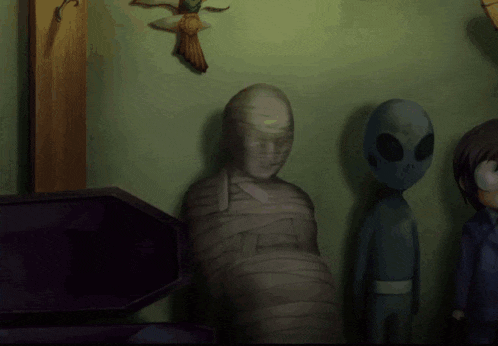 a statue of a mummy is surrounded by aliens and a cross