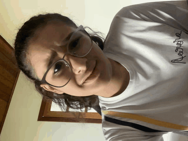 a girl wearing glasses and a white shirt that says restore on it