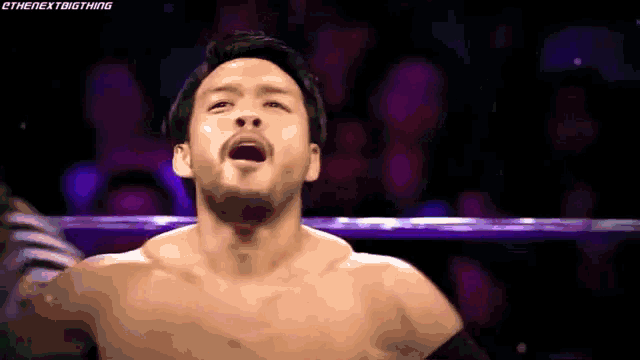 a man without a shirt is standing in a ring with his mouth open .