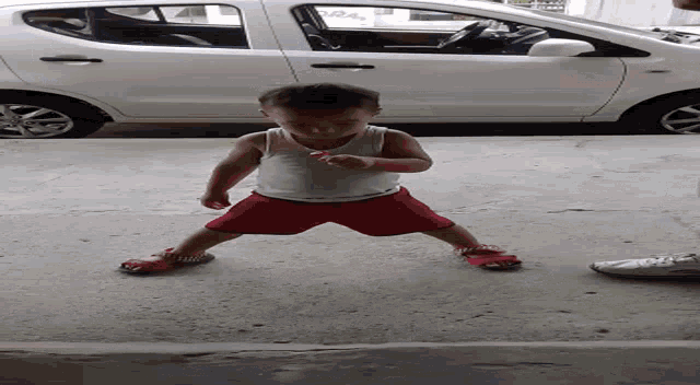 a little boy in red shorts is standing in front of a white van