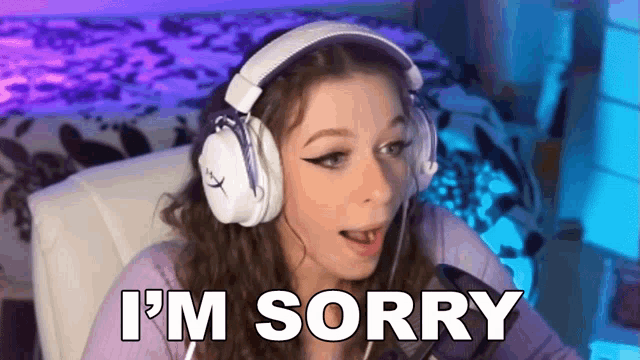 a woman wearing headphones says i 'm sorry while sitting in front of a computer