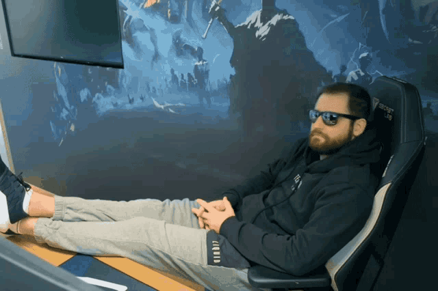 a man wearing sunglasses sits in a gaming chair