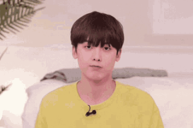 a young man wearing a yellow t-shirt and a microphone is making a face .