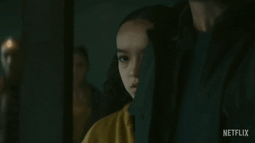 a young girl in a yellow jacket is looking at the camera .