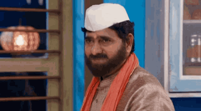 a man with a beard wearing a white hat and an orange scarf .