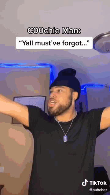 a man with a beard is wearing a beanie and a necklace and making a funny face .