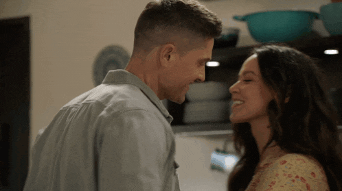 a man and woman are looking into each other 's eyes in a kitchen .