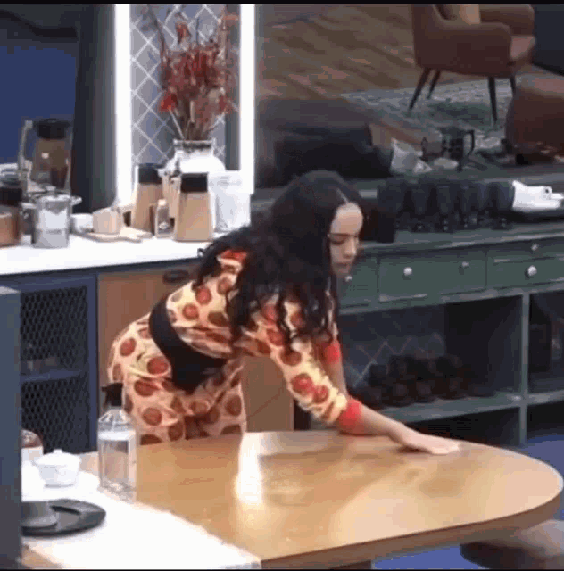 a woman is cleaning a table in a kitchen .