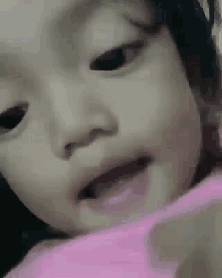 a close up of a baby 's face with a pink shirt on