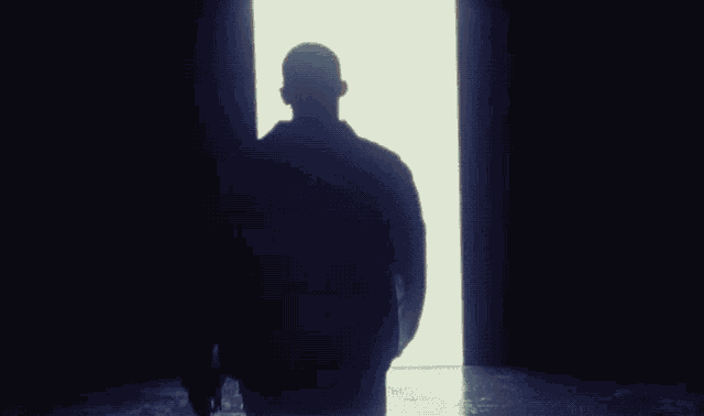 a silhouette of a person standing in a dark room
