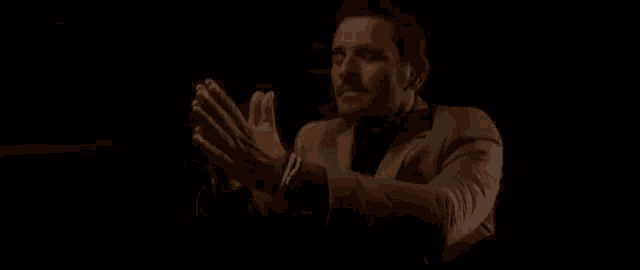 a man in a pink suit is clapping his hands in the dark .
