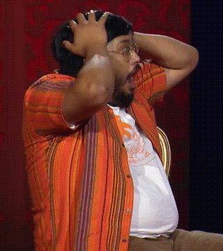 a man with glasses and a beard is holding his head with his hands