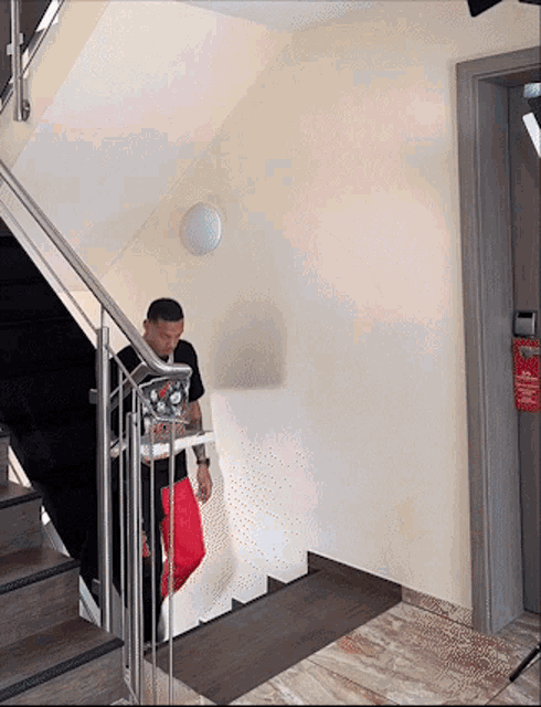a man standing on a set of stairs with a sign on the wall that says no smoking