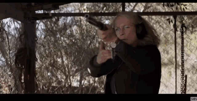 a woman wearing headphones is pointing a gun at someone