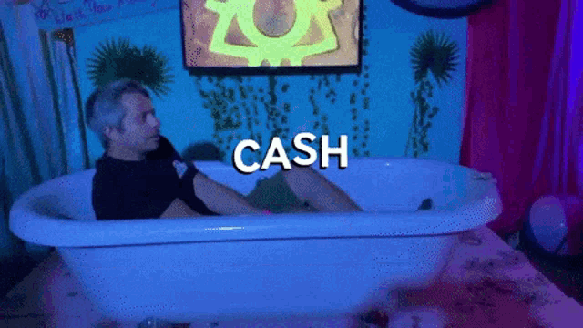 a man is laying in a bathtub with the word cash written on it