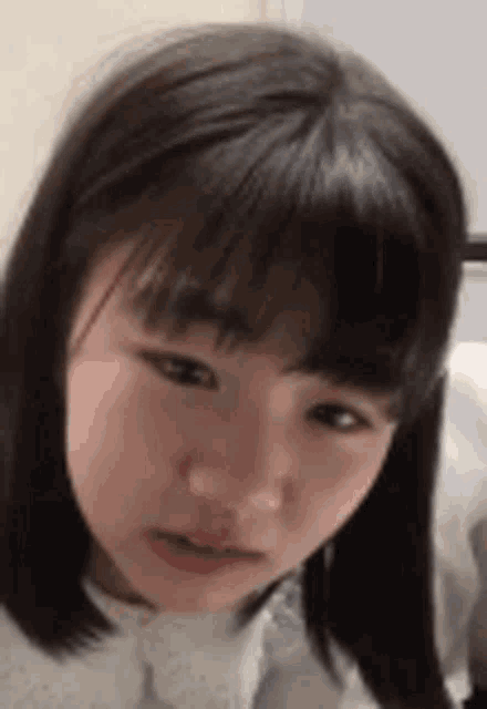 a close up of a girl 's face with short hair and bangs making a funny face .