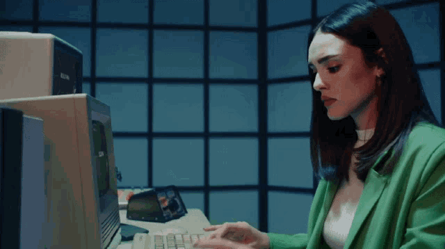 a woman in a green jacket is typing on an old fashioned keyboard