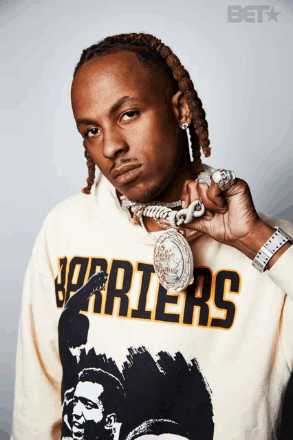 a man wearing a warriors sweatshirt is holding a necklace