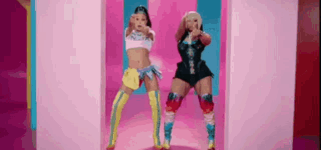a couple of women are standing next to each other in a pink room .