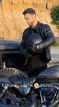 a man holding a helmet next to a motorcycle with gold latin music written on the bottom