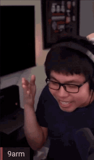 a man wearing glasses and headphones is smiling in front of a screen that says 9arm