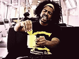 a man with curly hair wearing a black and yellow shirt that says conquer all