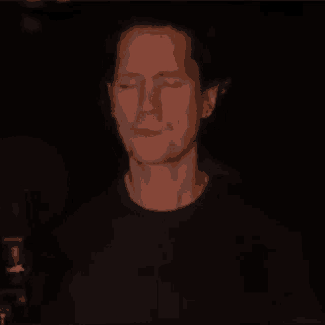 a man is standing in the dark with his eyes closed and his mouth open .