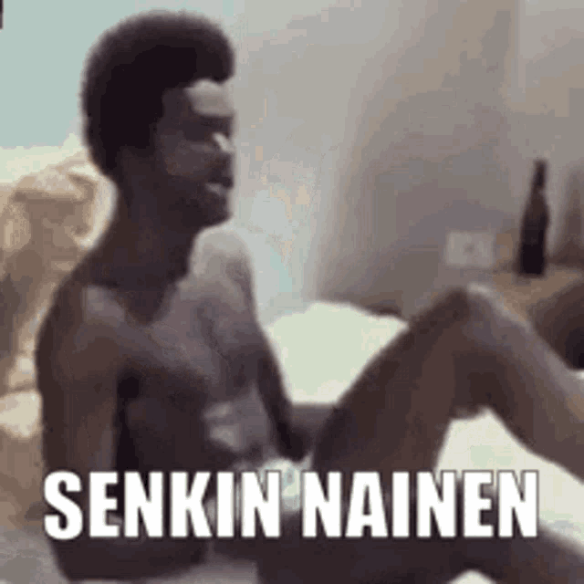 a shirtless man is sitting on a bed with his legs crossed and the words senkin nainen on the bottom .