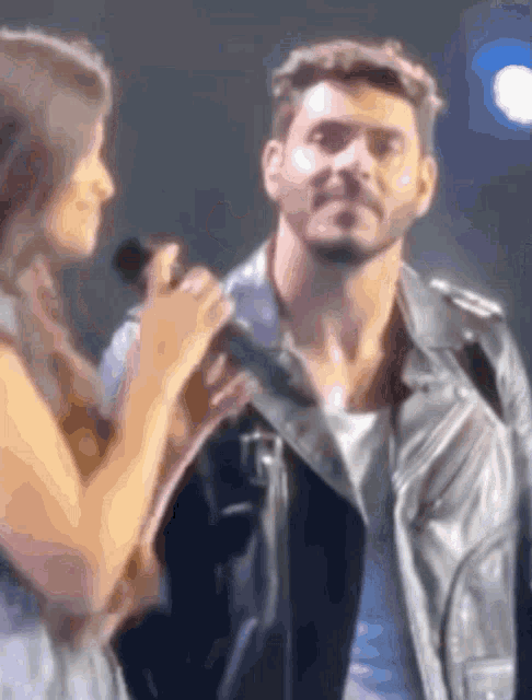 a man in a leather jacket and a woman singing into a microphone